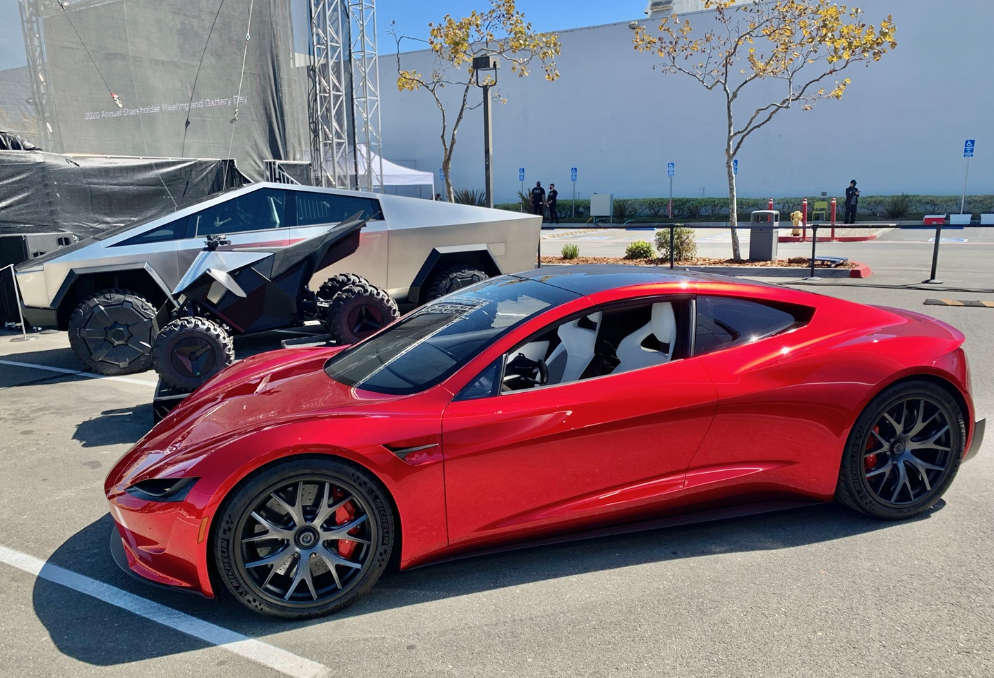 A red Tesla Roadster prototype is parked beside a Cybertruck at Tesla's 2020 shareholder meeting.